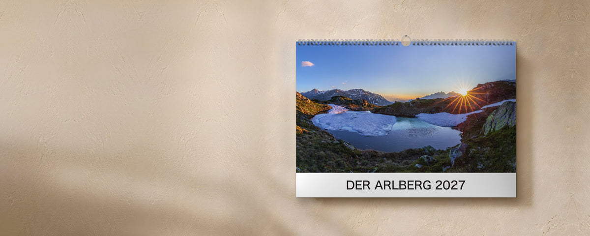 Der Arlberg 2027 wall calendar with silver wire binding hanging on a wall