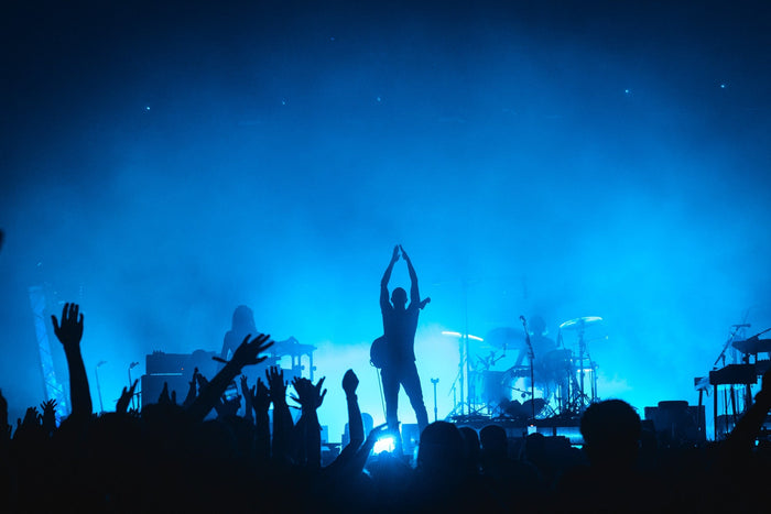 Band in silhouette against blue stage light with raised hands in front
