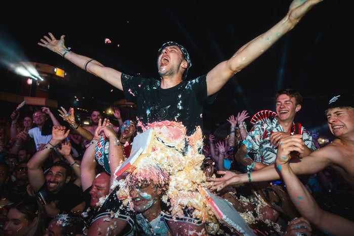 Visitor covered in cake cheering with open arms in the crowd