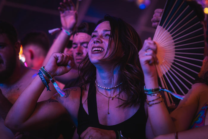 Visitor with a hand fan dancing in purple light