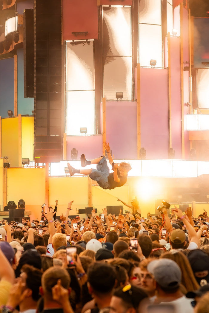 Crowd surfer flying over the audience in golden backlight
