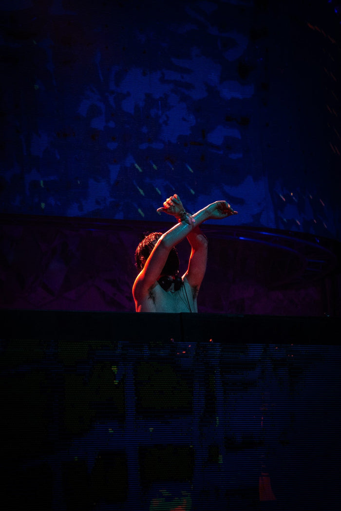 DJ crossing his arms above the decks in dark red light
