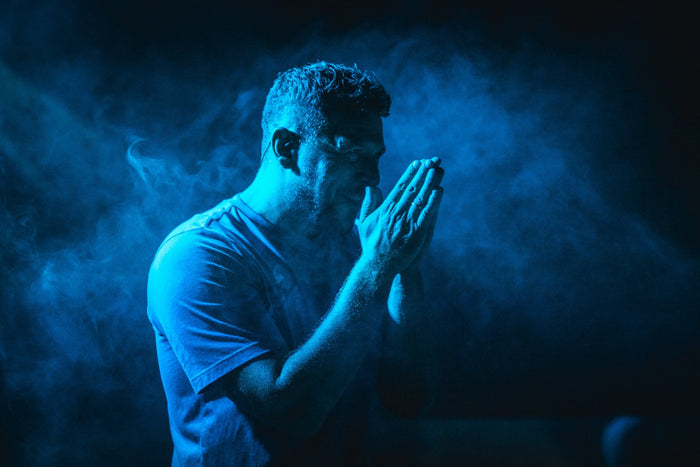 Artist holding his hands together in blue smoke on stage