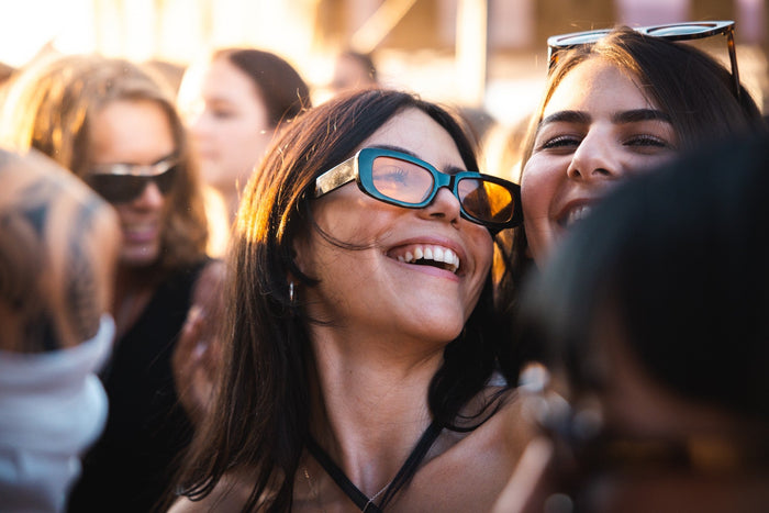 Two friends laughing together in golden evening light at a festival