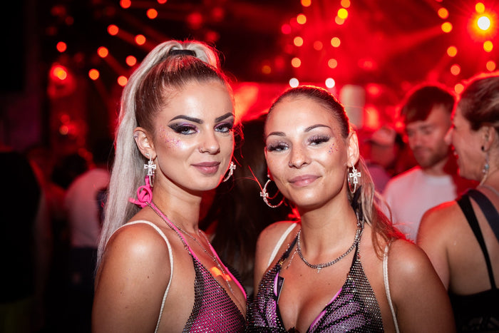 Two festival visitors with glitter make up in red light