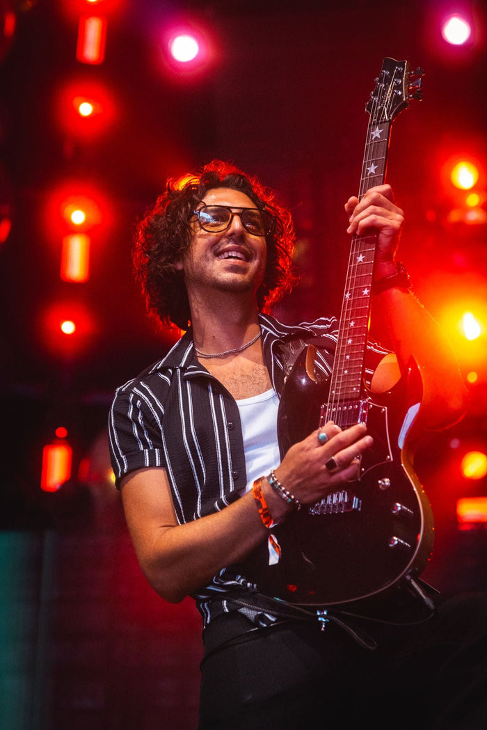 Guitarist smiling in front of red stage lamps