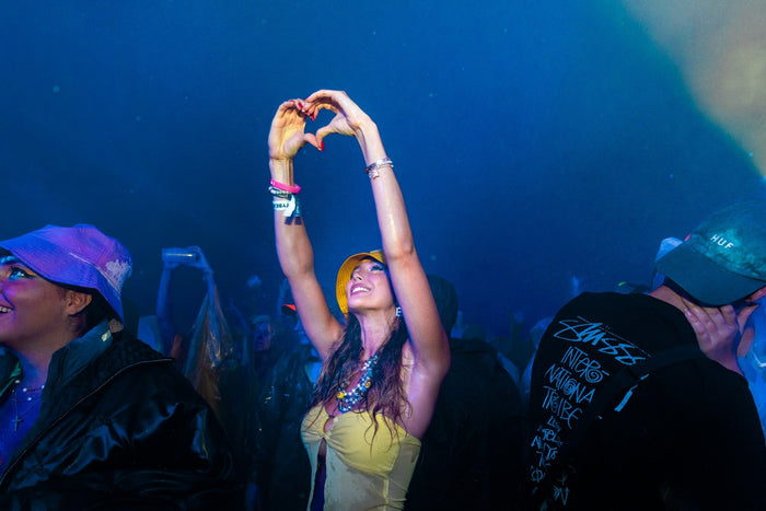 Festival visitor forming a heart with her hands in blue night light