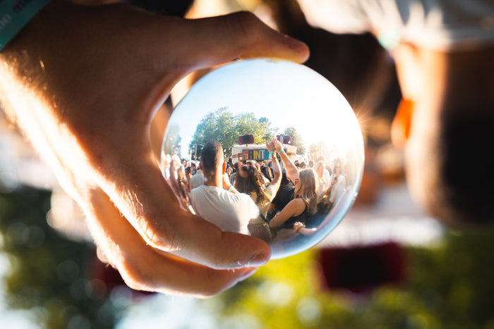 Festival crowd reflected in a glass ball held into the light