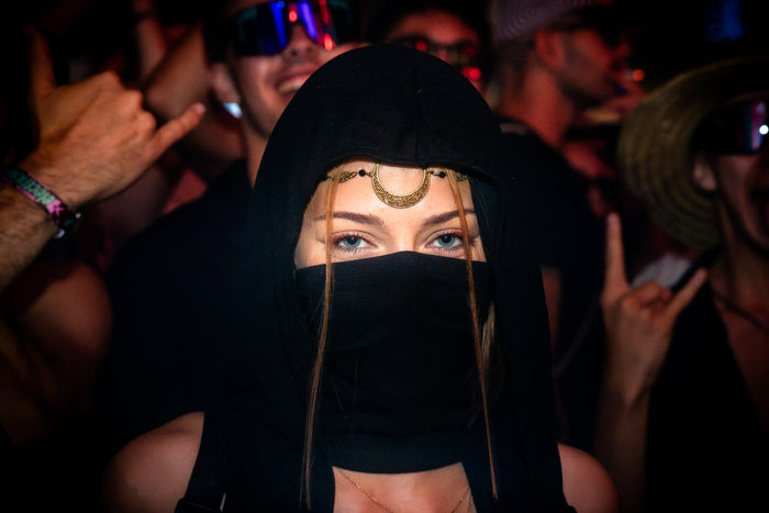 Portrait of a festival visitor with a hood and head jewellery at night