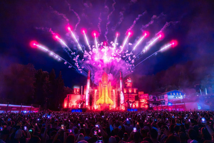 Rocket shaped stage with pink fireworks above the night crowd