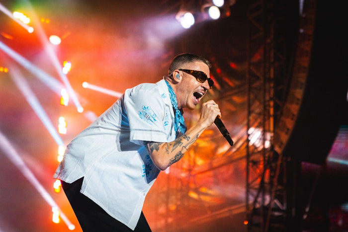 Singer performing into the microphone under red stage lights