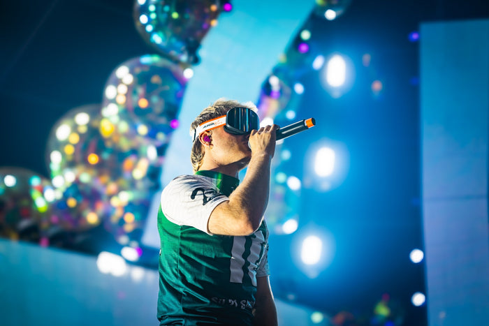 Singer with a visor performing between glitter balloons