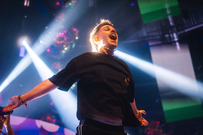 Singer with open arms in white light beams on stage