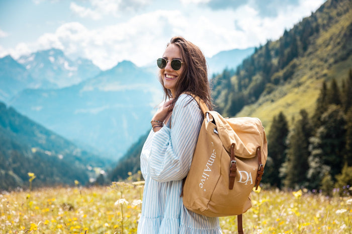 Smiling guest with a DreamAlive backpack in a flower meadow