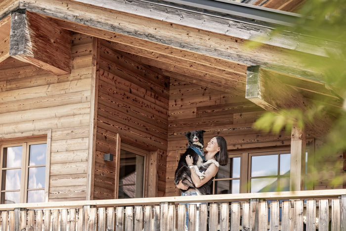 Guest holding her dog on the balcony of a wooden chalet