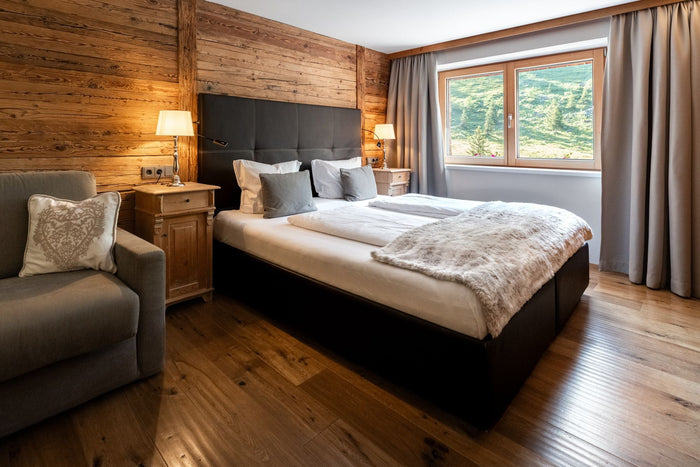 Hotel bedroom with old wood walls, warm lamps and a mountain window