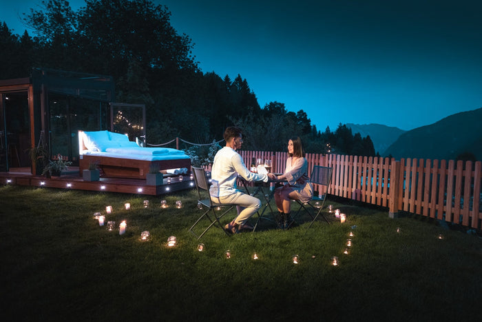 Candlelight dinner for two next to an outdoor bed at blue hour