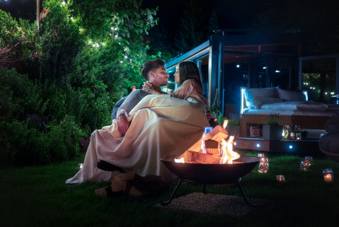 Couple under a blanket by a fire bowl at night