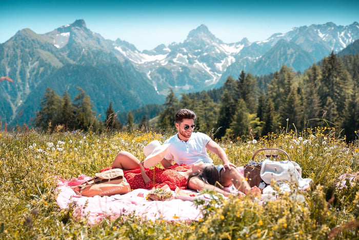 Couple having a picnic in a flower meadow below the mountains