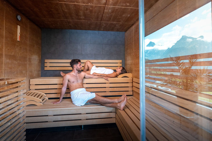 Couple relaxing in a sauna with a panoramic mountain window