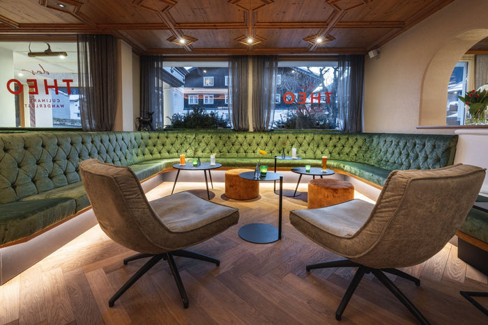 Hotel lounge with a green velvet bench and armchairs