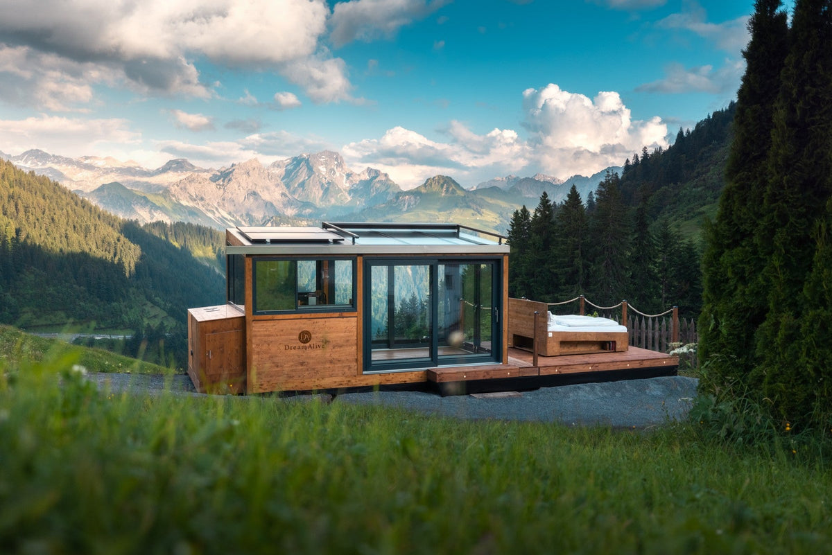 DreamAlive glass suite with outdoor bed in front of an alpine panorama