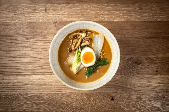 Ramen bowl with egg and mushrooms photographed from above on oak