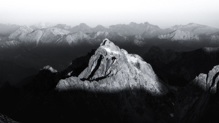 Black and white limestone peak in front of layered mountain ranges