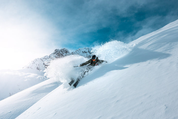Freerider blasting through deep powder straight towards the camera