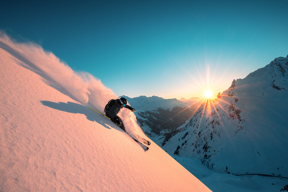 Freerider descending a powder face in warm sunset light at the Arlberg