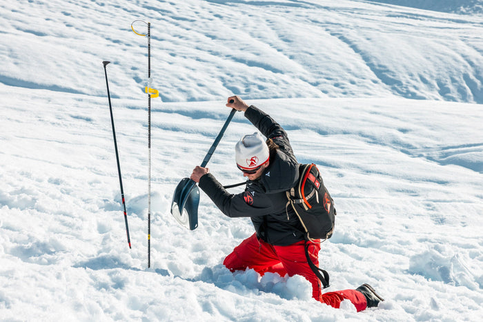 Instructor digging with an avalanche shovel next to a probe during training