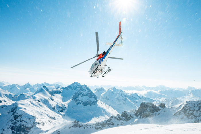 Helicopter flying off over snowy Arlberg peaks in bright sun