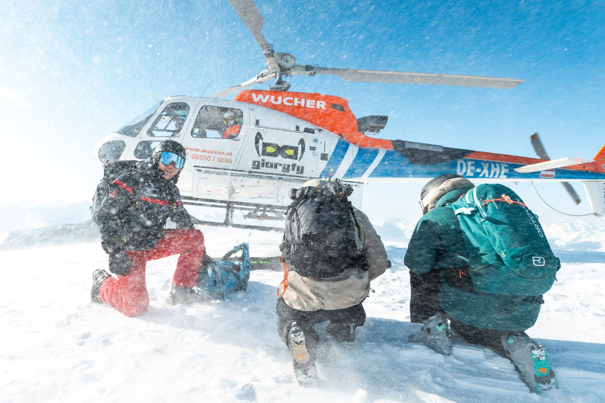 Heliskiing group crouching as the helicopter lifts off