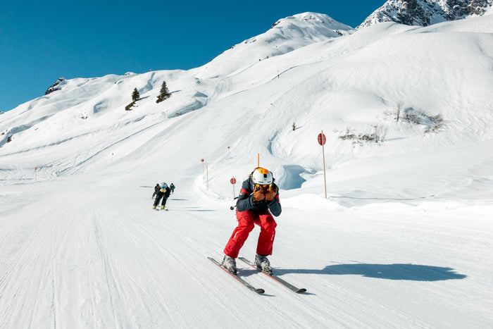 Ski instructor leading a group down a wide sunny piste
