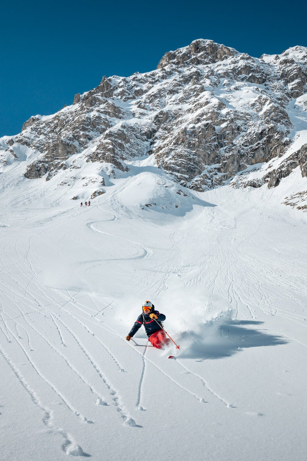 Skier in fresh powder below the rock face