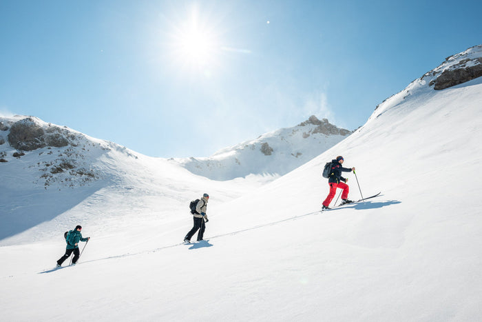 Three ski tourers climbing a sunny slope in Zürs