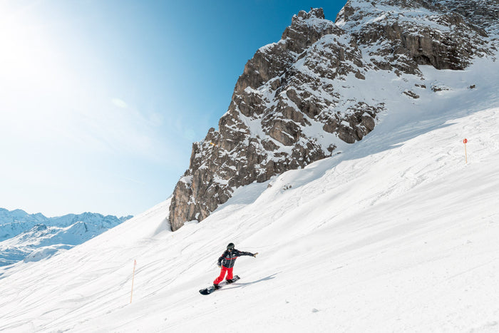Snowboard instructor riding below a rock face in Zürs