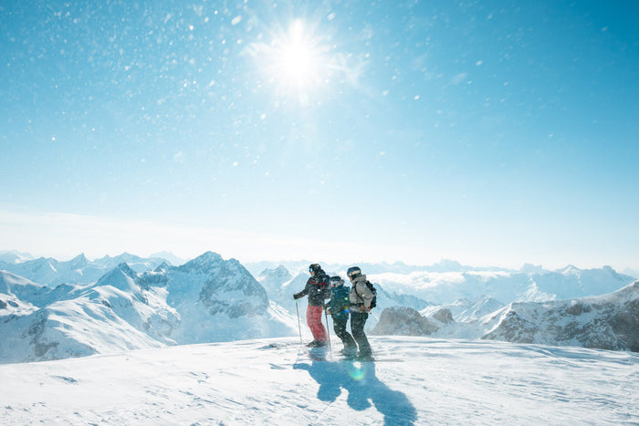 Three skiers on a sunny summit plateau before the heliski descent