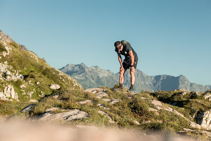 Trail runner catching his breath on a grassy summit