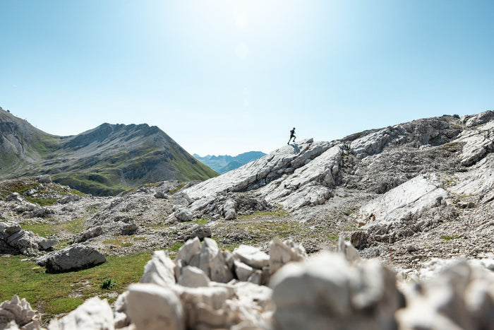 Trail runner crossing a white limestone ridge above Lech Zürs