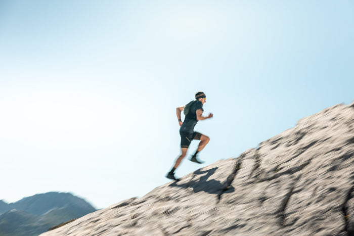 Trail runner sprinting up a rock slab in motion blur