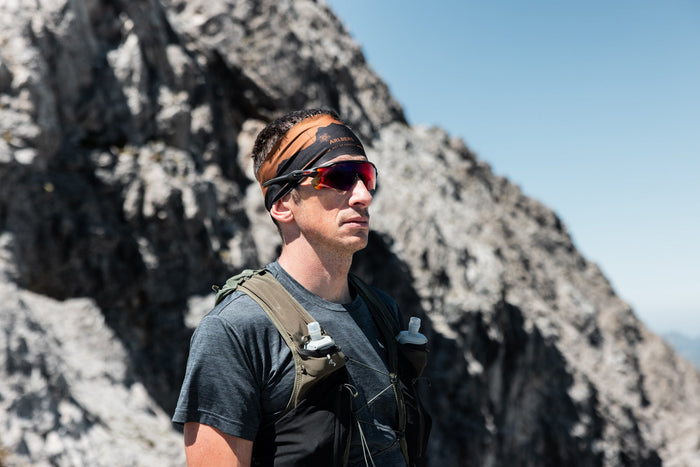 Portrait of a trail runner with an Arlberg headband in front of a rock face