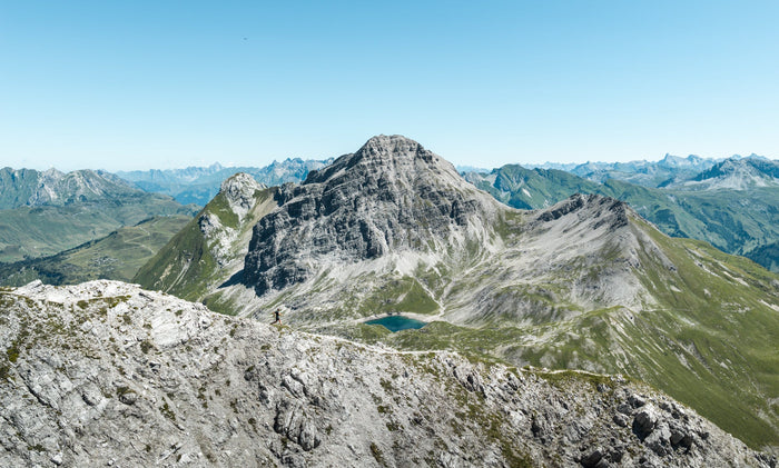 Drone view of a trail runner on a ridge above a mountain lake at the Arlberg