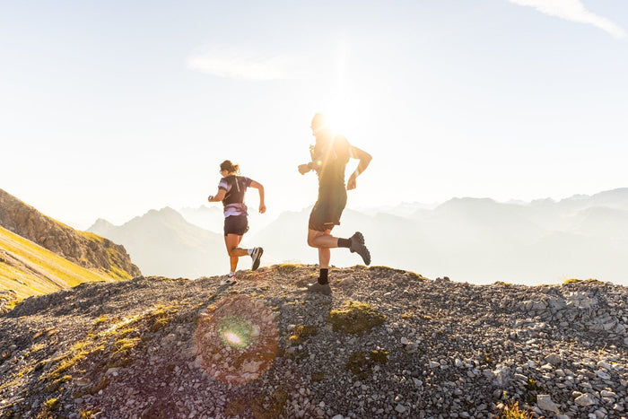 Two trail runners on a ridge in backlight above Lech Zürs