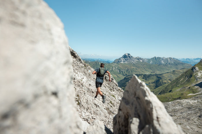 Trail runner on a rocky trail with a wide valley view near Lech