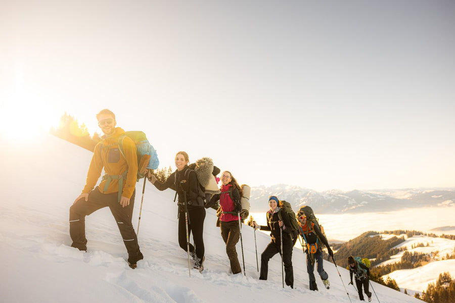 Community hiking up a snowy slope in the sun