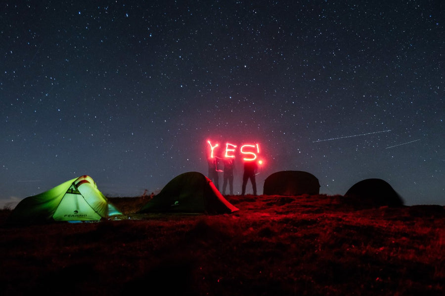 YES written in red light above tents under the stars
